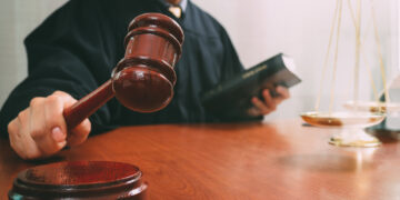 justice and law concept.Male judge in a courtroom with the gavel and working with holy book and brass scale on wood table
