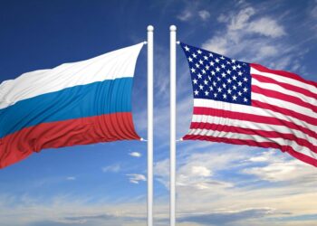 American and Russian flags against of blue sky