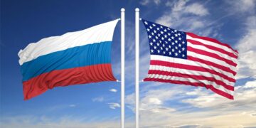 American and Russian flags against of blue sky