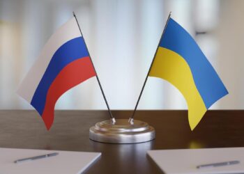 Ukrainian and russian flags on table. Negotiation between Russia and Ukraine. 3D rendered illustration.