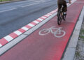 Germany, Berlin, Schöneberg, August 05, 2024 -Cyclist on a red bike path on a street in the city