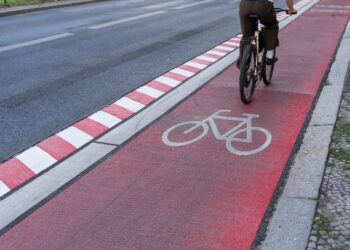 Germany, Berlin, Schöneberg, August 05, 2024 -Cyclist on a red bike path on a street in the city