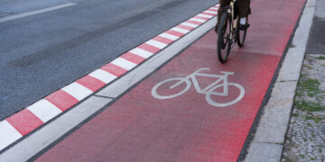 Germany, Berlin, Schöneberg, August 05, 2024 -Cyclist on a red bike path on a street in the city