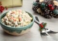 Traditional russian salad Olivier served on white wooden table