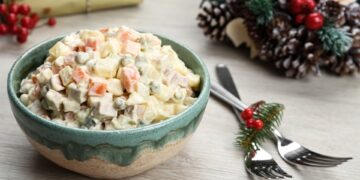 Traditional russian salad Olivier served on white wooden table